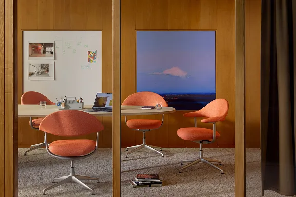 Orangefarbene Bürostühle der Serie Mynt stehen in einem modernen Büro am Schreibtisch.