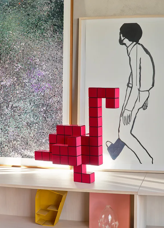 Eine pinke Panton-Cubes-Skulptur in Flamingo-Form steht vor gerahmten Kunstwerken auf einem Sideboard.
